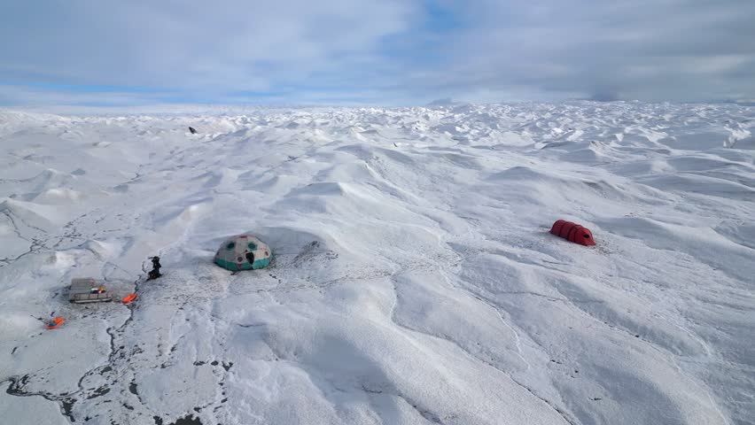 Aerial orbits large dome tent in ecotourism camp on vast ice glacier