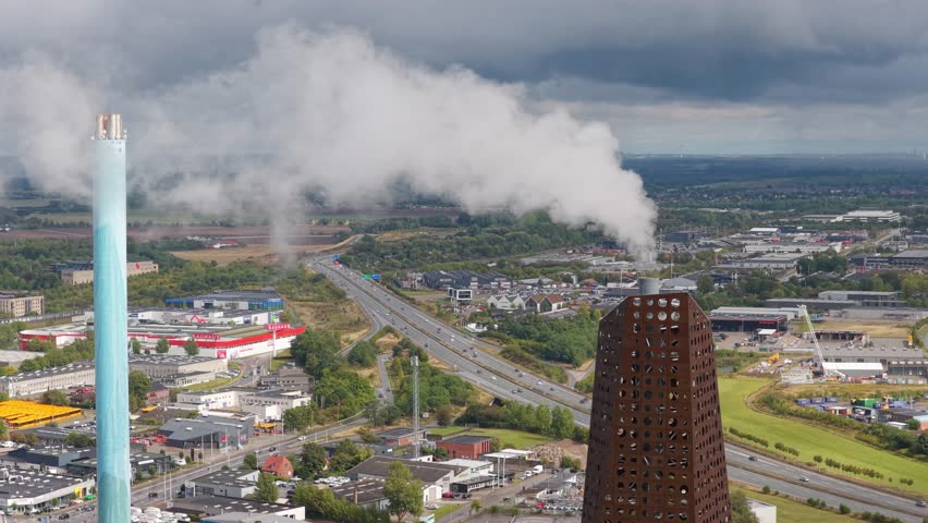 Aerial drone view of a working power plant with smoke plume, showing electricity generation infrastructure and heavy industry in action.