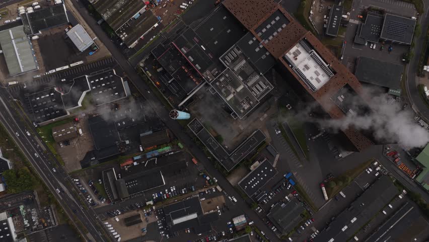 Aerial drone view of a working power plant with smoke plume, showcasing electricity generation infrastructure and heavy industry.
