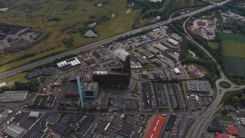 Overhead view of a utility plant producing energy—visible steam plume, cooling systems, and transmission lines feeding the network.