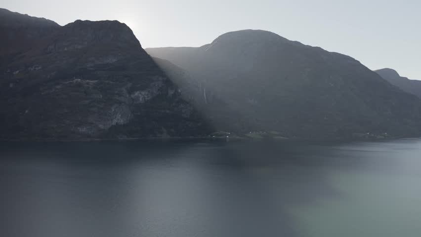 Flying over Lusterfjorden fjord towards Feigefossen waterfall. Beautiful sun light falls on the fjord over the mountain. Drone footage