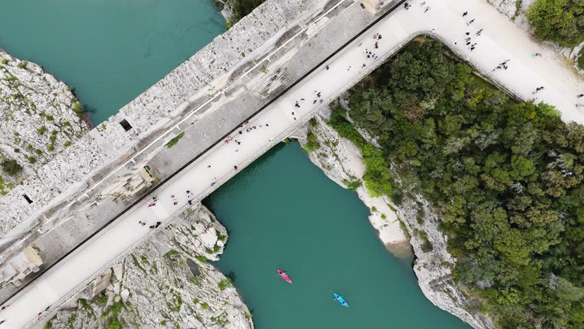 Drone glides above Pont du Gard, revealing its monumental scale contrasted with tiny figures below
