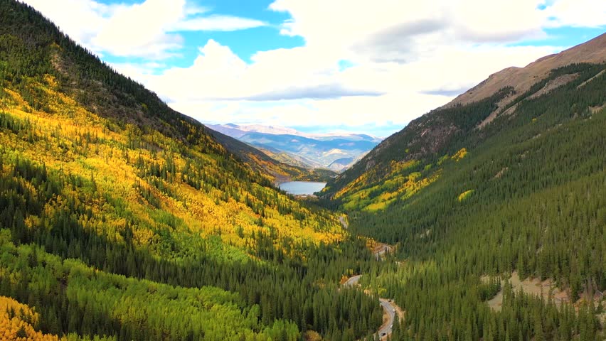 The Sierra Madre Mountains of New Mexico shimmer with fall color as winding roads cut through ridges filled with bright trees and rocky peaks.