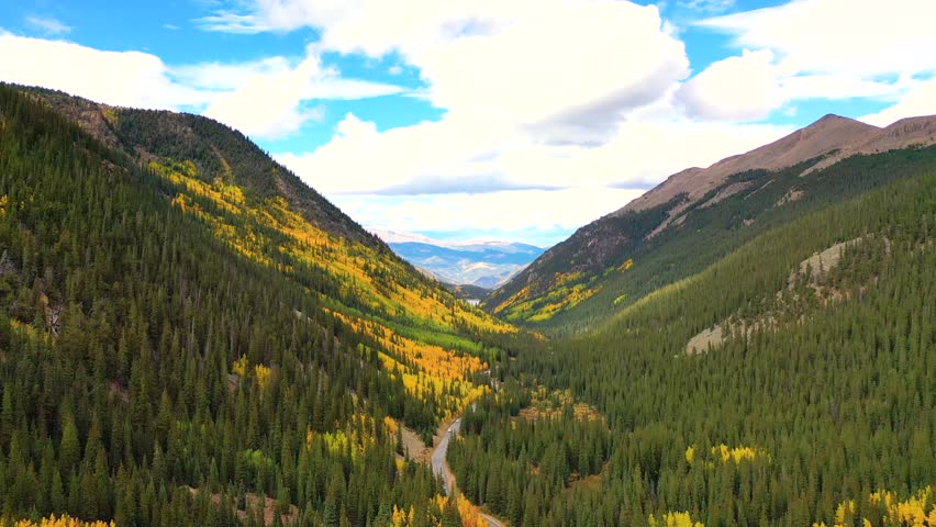The Andes Mountains stretch across the horizon as drone footage captures fall color covering alpine roads, distant peaks, and sweeping mountain valleys.