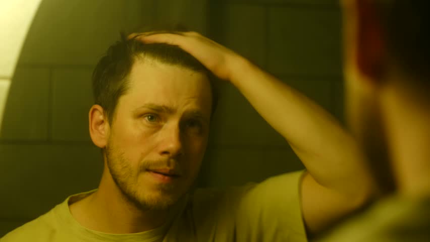 Middle aged man looking in mirror, anxiously checking for hair loss and balding, then gaining confidence, pointing at his reflection with smile. Happy confidence man. Concept of self confidence. 