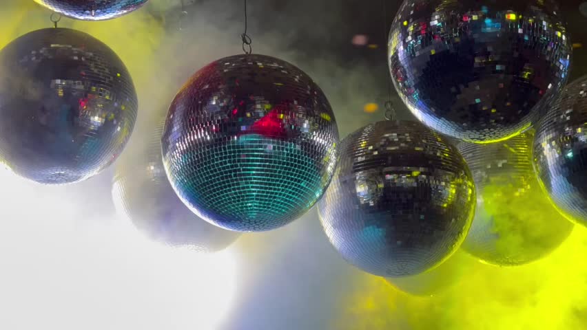 Close up of Disco Balls with Colorful Lights and Smoke, hanging from the ceiling.