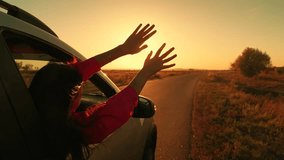 Young female passenger catches wind with hands from car window. Beautiful girl student in car drives road to meet sunrise. Family trip, teenage girl traveling by auto. Family vacation. People travel - Powered by Shutterstock - Get 15% off with code: PIKWIZARD15