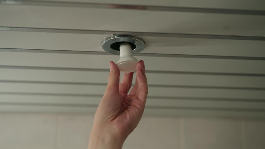 Electrician changing round led lightbulb in recessed ceiling fixture, performing routine indoor home improvement, maintenance, repair, providing proper lighting, close-up. Shooting in slow motion.