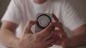 Close-up cropped shot of man setting mechanical timer switch, device used to control the on off cycles of electrical appliances, promoting energy efficiency and convenience in household management. - Powered by Shutterstock - Get 15% off with code: PIKWIZARD15