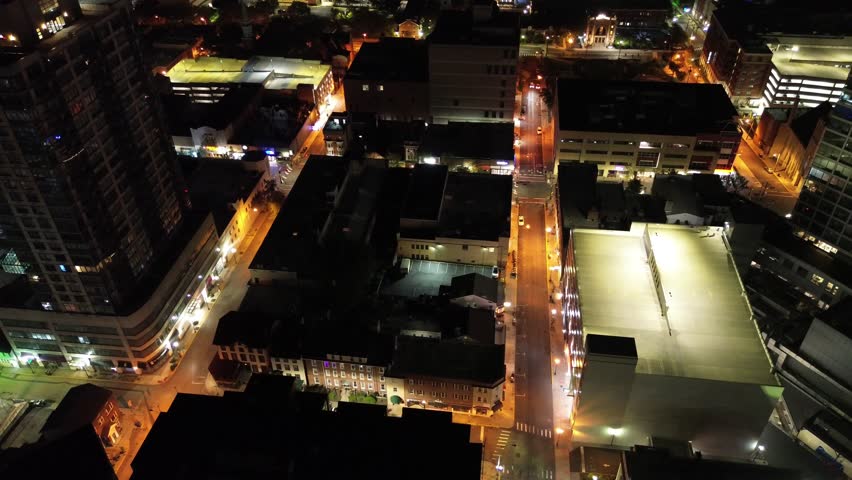 
Nighttime aerial view in motion circling around a block of downtown New Brunswick, NJ high-rises leading into focusing focusing on the street below.