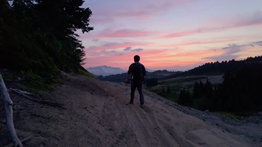 Hiker Walks Towards a Majestic Sunset Over Snow-Capped Mountains in Whistler, British Columbia
