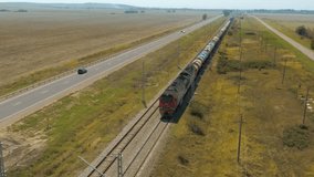Aerial drone view freight train moving through countryside parallel to highway, industrial cargo transportation, logistics railway infrastructure in rural landscape. rural street road. railroad rail - Powered by Shutterstock - Get 15% off with code: PIKWIZARD15