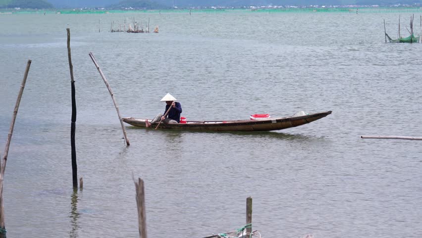 Hue, Vietnam - July 5th, 2025: The silhouette of a fisherman boarding a boat to go fishing in a lagoon at dawn in central Vietnam