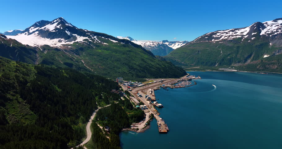 Town of Alaska located in the stunning snow-capped mountains on the river waterfront. Drone footage over the scenery on a clear day.