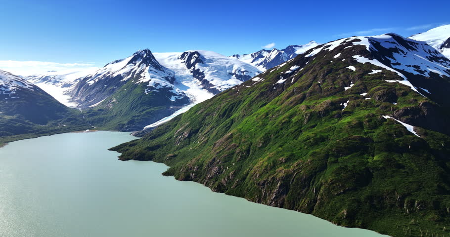 Breath-taking scenery of spectacular mountains covered with snow. Drone footage over the peaceful blue waterscape. Alaska wilderness, USA.