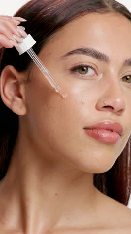 Face, happy woman and beauty in studio with serum for skincare, dermatology and collagen benefits. Confident, person and hyaluronic acid for hydration, healthy skin and wellness on white background.