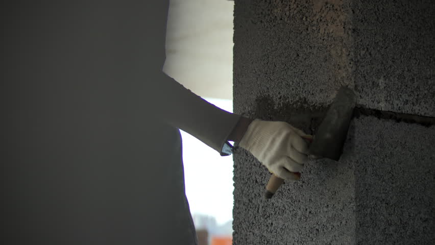 Worker applying mortar between concrete wall blocks