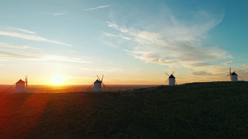 Aerial view of the historic windmills of Consuegra at sunrise, Castilla-La Mancha, Spain. Old historic windmills of Don Quixote character on the hills in morning light. Molinos de Viento de Consuegra