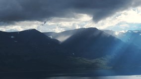 Moody storm cloud breaks above Lake Lama as sunbeam sweeps dark Putorana slopes. Soft haze and shadow create cinematic depth over the taiga shoreline, promising adventure and pristine wilderness - Powered by Shutterstock - Get 15% off with code: PIKWIZARD15