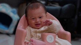 Asian Calm adorable infant toddler pink baby chair with soft light indoor living room cozy home, candid moment cute expression, baby reaching hand small hands finger near mouth, chubby girl or boy - Powered by Shutterstock - Get 15% off with code: PIKWIZARD15