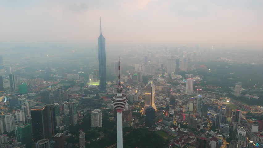 The Petronas Twin Towers anchor the luminous grid as blue hour arrives over Kuala Lumpur. The flight opens wide over KLCC, reflecting steel symmetry, city rhythm and premium travel allure for visitors