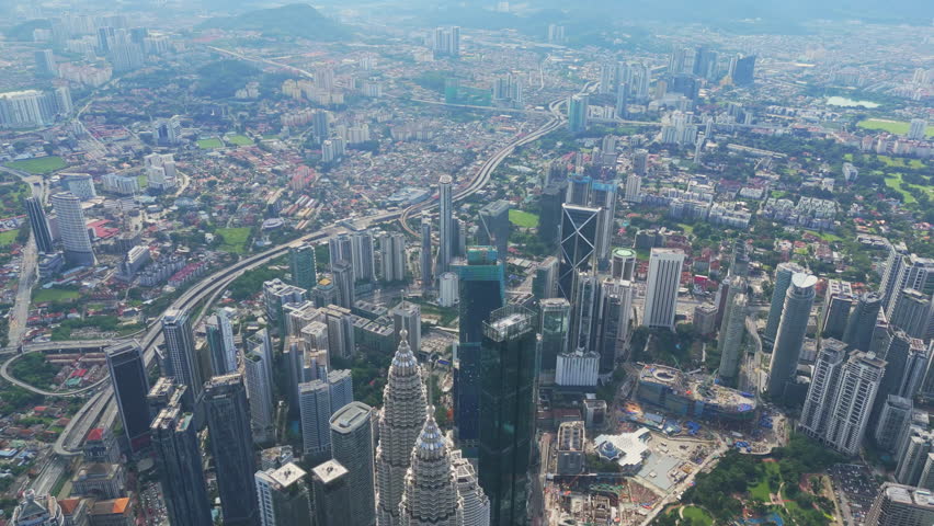 Wide panorama of Kuala Lumpur with Petronas Towers, TRX and sprawling suburbs under clear midday light. Malaysia capital skyline, travel destination, business hub and modern architecture highlight