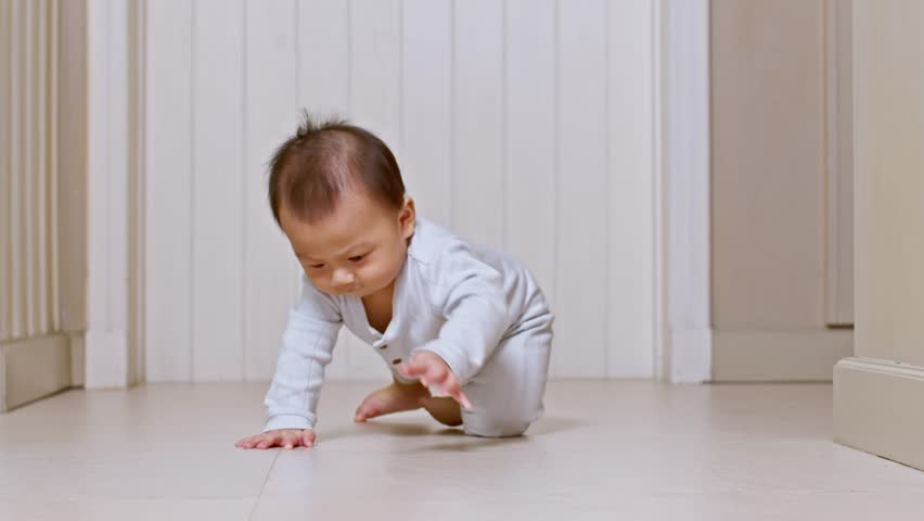 Asian Baby infant toddler crawling on indoor floor wearing white pajamas looking up with curious expression bright room child exploring surroundings quietly