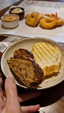Panning shot over restaurant table with gourmet dishes. Shows escargots in cream sauce, fried tempura shrimp, oysters with lemon, and bowl of chicken soup, presenting a complete fine dining experience
