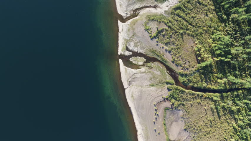 Aerial view straight down to sandy inlets where a small stream enters Lake Lama on the Putorana Plateau, Russia. Clear water gradient, minimal wake, graphic coastline, useful for map, travel and envir