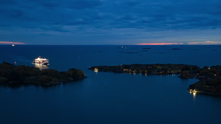 Aerial hyperlapse of the a illuminated shuttle passing islands, dusk in Helsinki