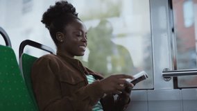 African American woman sitting on green seat reading book in moving bus. Female smiling and focusing on pages. Cityscape visible behind window glass. Passenger enjoying travel time. - Powered by Shutterstock - Get 15% off with code: PIKWIZARD15