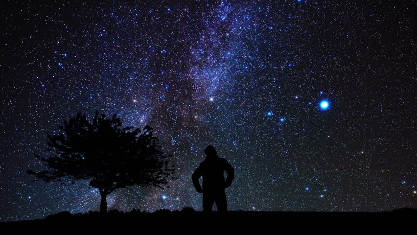 Silhouette of a man and countryside under the Milky Way stars.