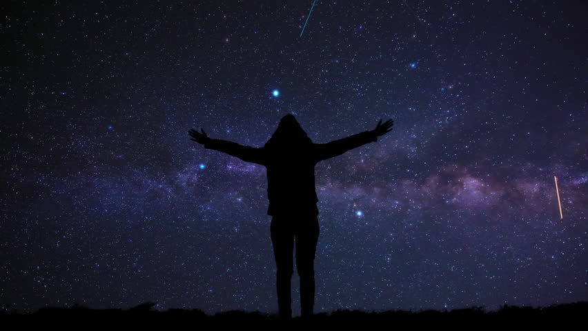 Woman with arms wide open enjoying outdoors under stars, planets and Milky way.