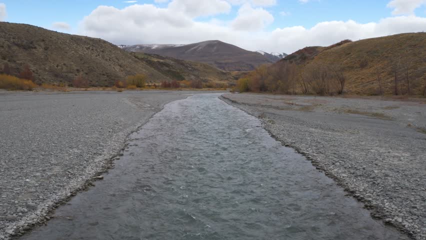 River Flowing Through Mountainous Landscape With Rocky Terrain In South Island, New Zealand - Wide Shot