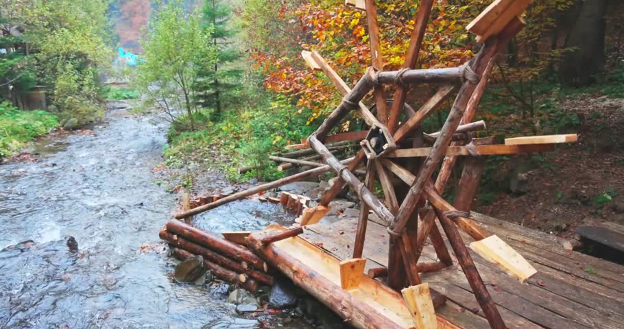A working wooden water wheel next to a mountain stream.