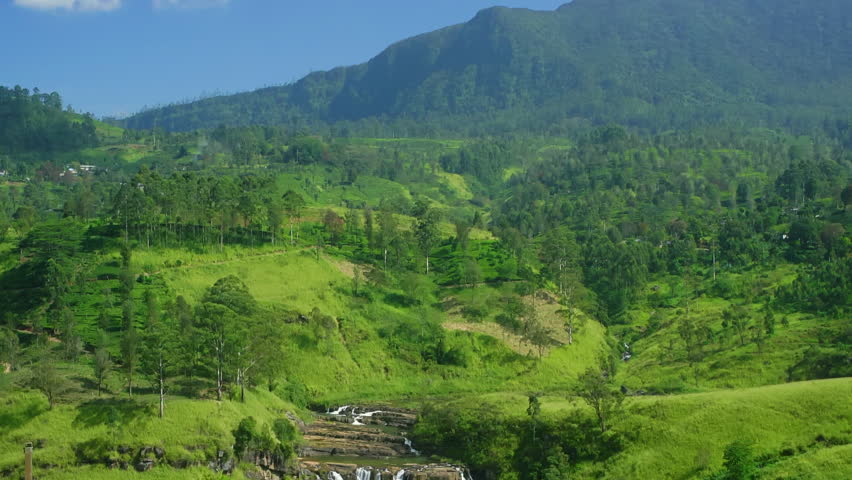 Scenic beauty of St. Clair's Falls, a tiered waterfall cascading down lush green hills, surrounded by tea plantations in Sri Lanka, creating a breathtaking view of nature's splendor