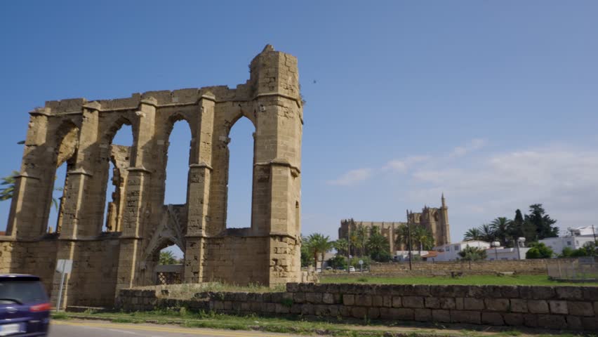 Ruins of a historic church in Northern Cyprus, showing ancient stone architecture, arched windows, and detailed masonry under a clear blue sky