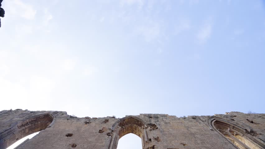 Ruins of a historic church in Northern Cyprus, showing ancient stone architecture, arched windows, and detailed masonry under a clear blue sky