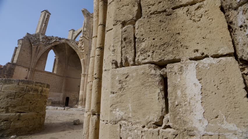 Ruins of a historic church in Northern Cyprus, showing ancient stone architecture, arched windows, and detailed masonry under a clear blue sky