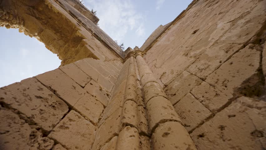 Ruins of a historic church in Northern Cyprus, showing ancient stone architecture, arched windows, and detailed masonry under a clear blue sky
