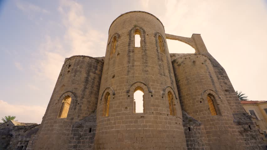 Ruins of a historic church in Northern Cyprus, showing ancient stone architecture, arched windows, and detailed masonry under a clear blue sky
