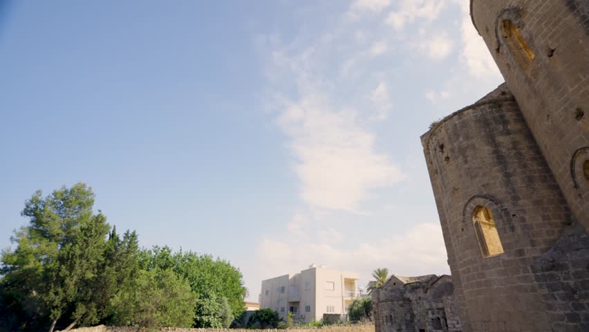 Ruins of a historic church in Northern Cyprus, showing ancient stone architecture, arched windows, and detailed masonry under a clear blue sky