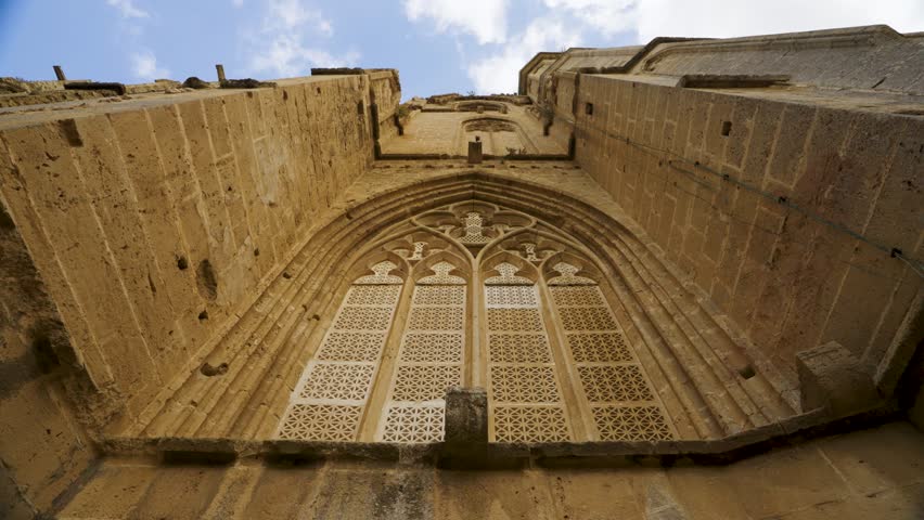 Ruins of a historic church in Northern Cyprus, showing ancient stone architecture, arched windows, and detailed masonry under a clear blue sky