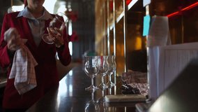 Female bartender wiping and polishing glasses arranged on shelves behind the bar counter, preparing for opening time, representing hospitality service. Restaurant business lifestyle concept. - Powered by Shutterstock - Get 15% off with code: PIKWIZARD15
