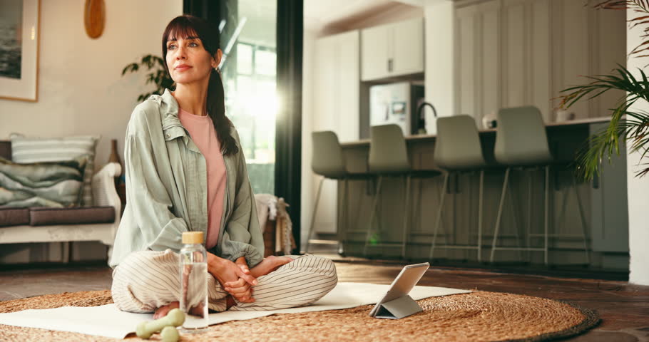 Fitness, woman and drinking water in lounge with tablet, indoor exercise or streaming video for thirst. Hydration, online workout class and person relax with liquid in home, break or rest on yoga mat