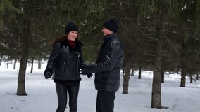 Young romantic couple wearing black winter clothes joyfully holding hands, dancing and spinning together in a snowy pine forest - Powered by Shutterstock - Get 15% off with code: PIKWIZARD15