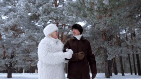 Happy elderly couple in warm fur coats walking arm in arm and chatting together in a beautiful snow covered pine forest in winter - Powered by Shutterstock - Get 15% off with code: PIKWIZARD15