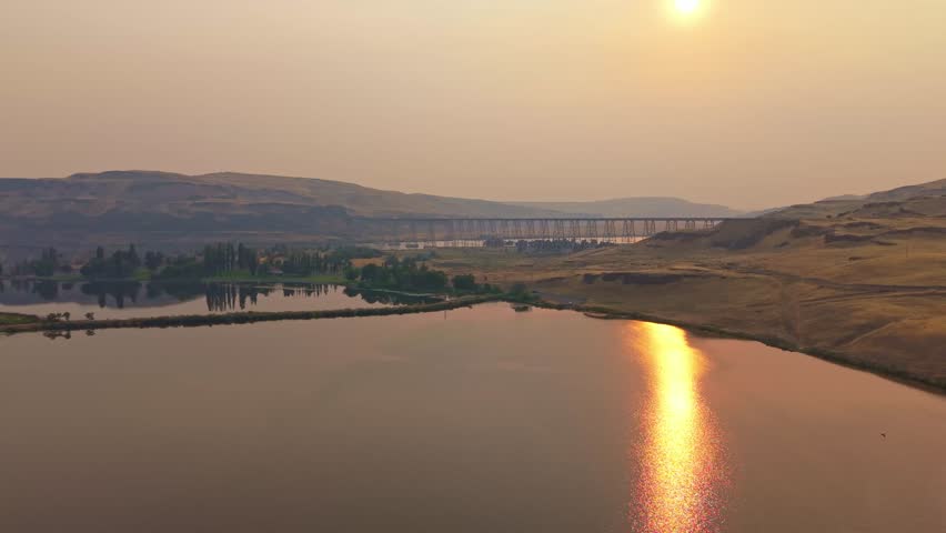 A breathtaking aerial view of the Lyons Ferry Bridge spanning the tranquil waters at Lyons Ferry State Park in Washington, bathed in the warm, golden light of sunset