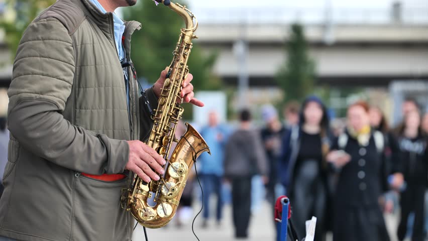 Street musician playing saxophone performing for crowd outdoors