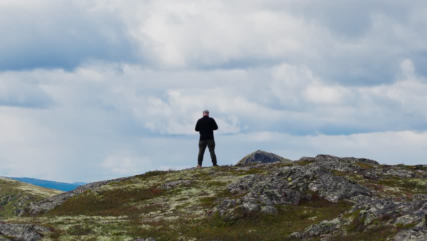 Epic Drone Ascending Shot Revealing a Breathtaking Vist of a Hiker on a Mountain Plateau Overlooking a Vast Lake and Rugged Highland Landscape